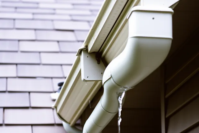 Rain gutter and downspout on a house after rain. Starting a gutter service business: the real startup costs and how owners fund them